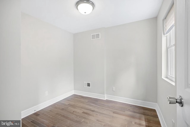 spare room with baseboards, visible vents, and wood finished floors