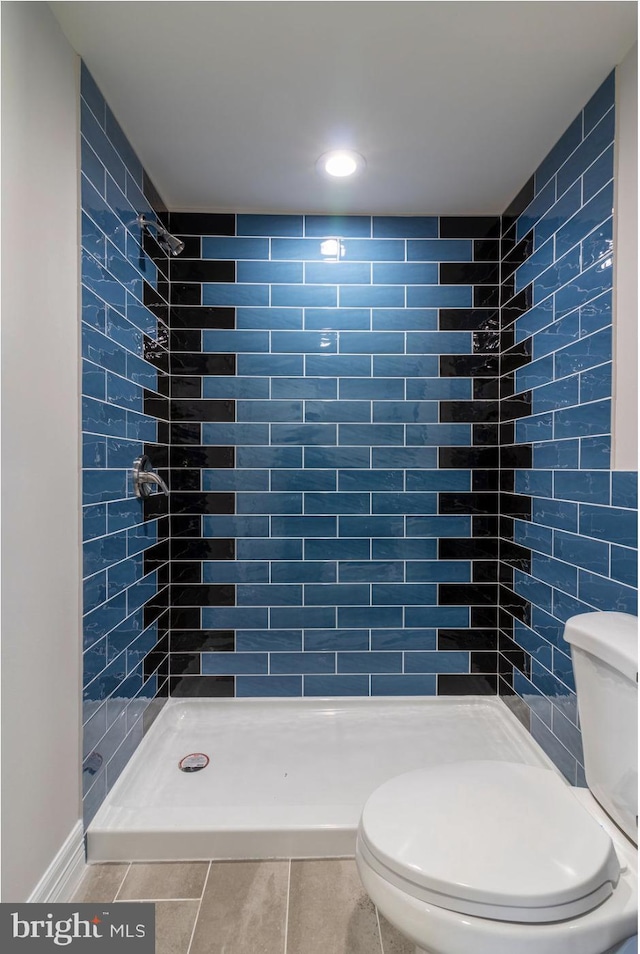 bathroom with toilet, tile patterned flooring, and a shower stall