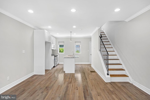 interior space featuring light wood-style flooring, recessed lighting, a sink, stairs, and crown molding