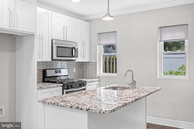 kitchen featuring a sink, stainless steel appliances, tasteful backsplash, white cabinetry, and light stone countertops