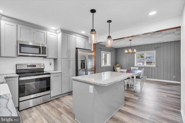 kitchen with hanging light fixtures, an inviting chandelier, light wood finished floors, appliances with stainless steel finishes, and gray cabinetry