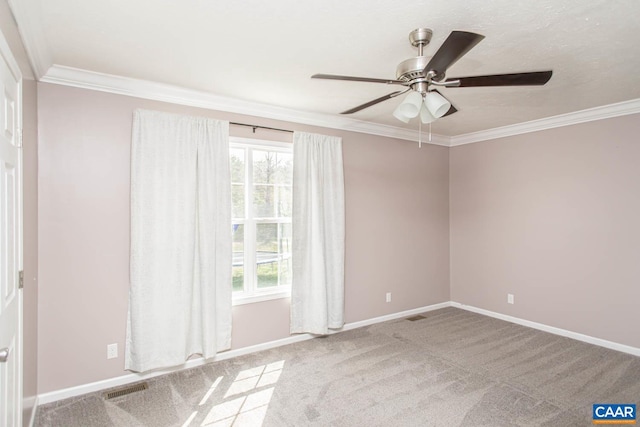 carpeted spare room featuring plenty of natural light, visible vents, crown molding, and ceiling fan