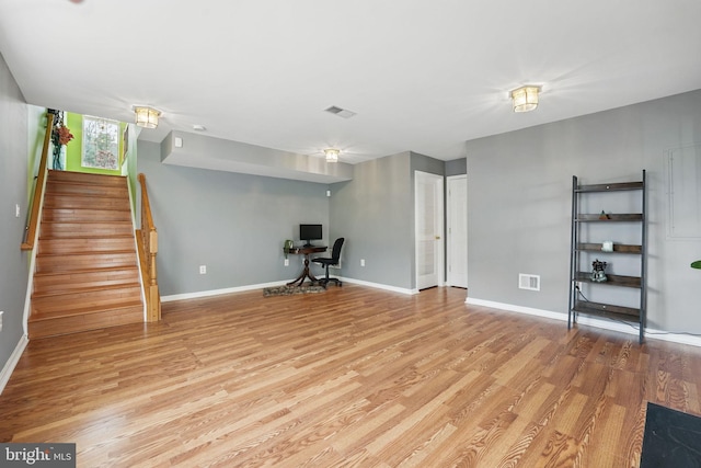 basement featuring baseboards, visible vents, wood finished floors, and stairs