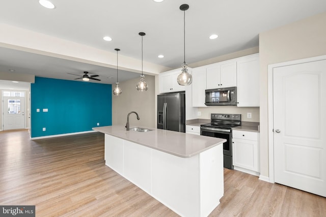 kitchen featuring stainless steel appliances, light wood-style flooring, a sink, white cabinetry, and a ceiling fan