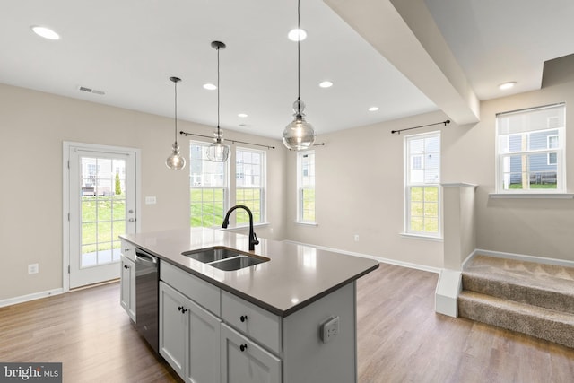 kitchen featuring open floor plan, light wood finished floors, stainless steel dishwasher, and a sink
