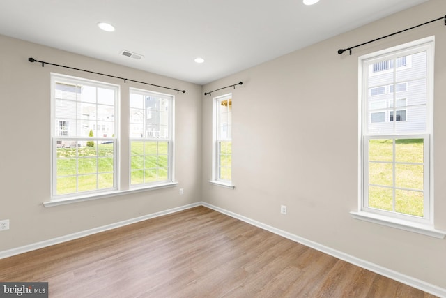 empty room with a healthy amount of sunlight, light wood finished floors, and baseboards