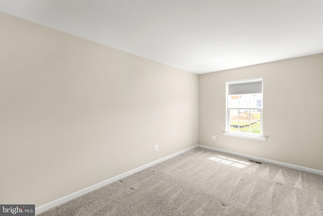carpeted empty room featuring baseboards and visible vents