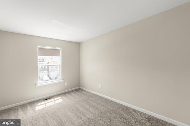 empty room featuring carpet floors, visible vents, and baseboards