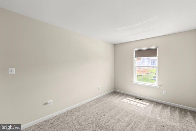 carpeted spare room with visible vents and baseboards
