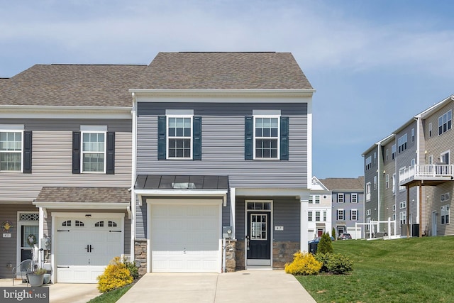 townhome / multi-family property with metal roof, a front lawn, concrete driveway, a standing seam roof, and a garage