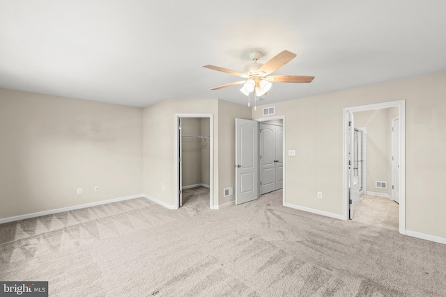 unfurnished bedroom with a walk in closet, carpet floors, visible vents, and baseboards