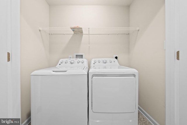 washroom with washing machine and clothes dryer and baseboards