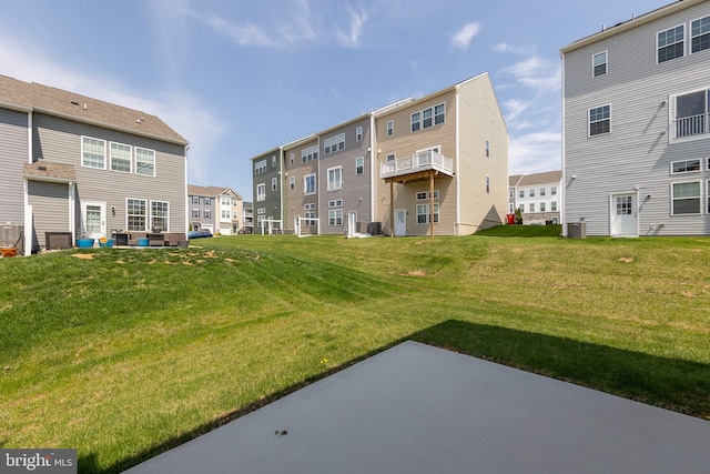 rear view of property with a lawn, central air condition unit, and a patio area