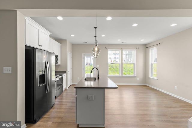 kitchen featuring baseboards, a sink, light wood-style floors, and appliances with stainless steel finishes