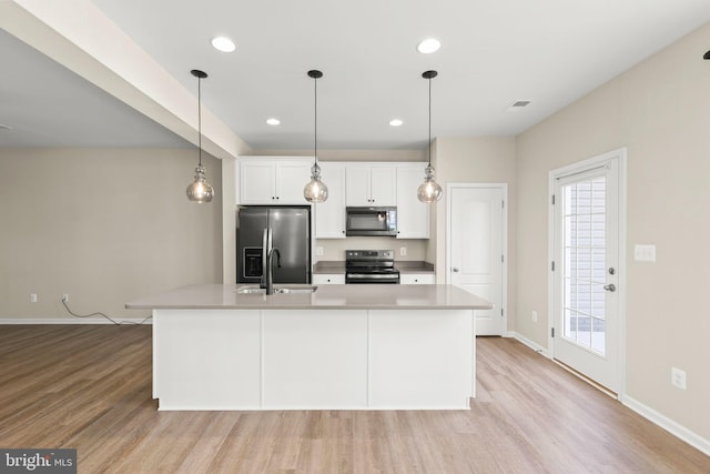 kitchen featuring white cabinets, light wood-style flooring, stainless steel appliances, and a sink