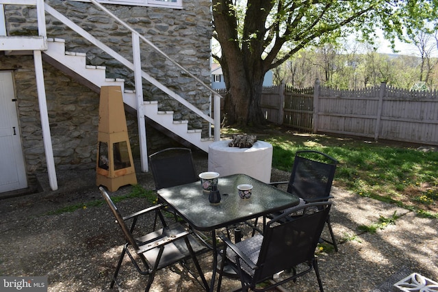 view of patio / terrace featuring fence, outdoor dining area, and stairs