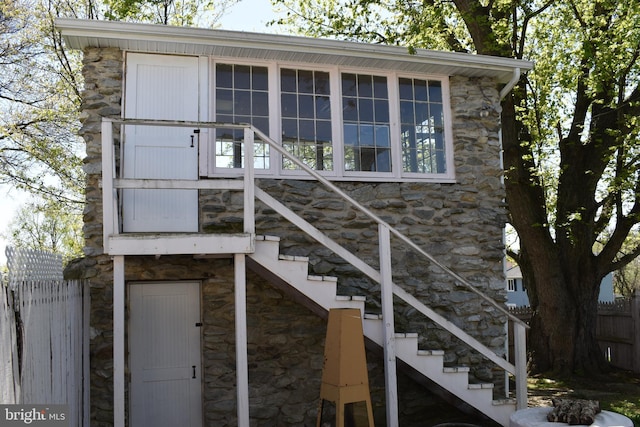 doorway to property featuring stone siding and fence