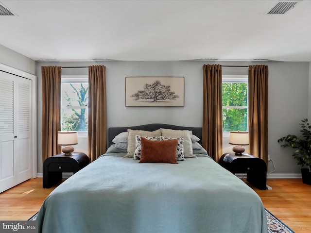 bedroom with light wood finished floors, multiple windows, and visible vents