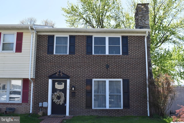 townhome / multi-family property featuring a chimney and brick siding
