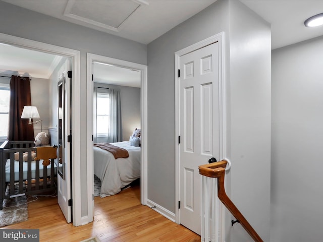 corridor with attic access and light wood-style flooring