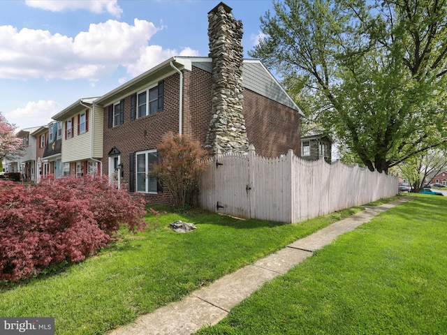 view of property exterior with brick siding, a lawn, and fence