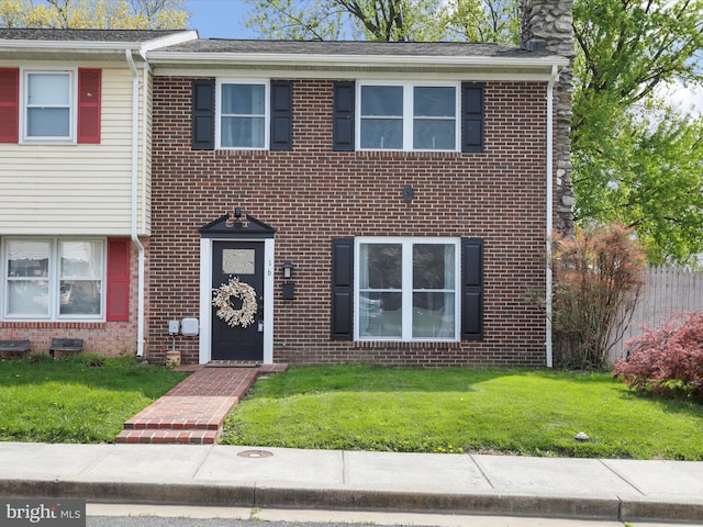 view of property with a front lawn, brick siding, and a chimney