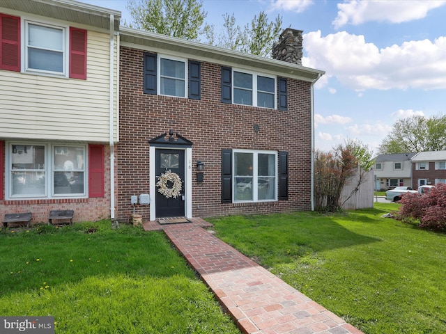 multi unit property with a chimney, brick siding, and a front yard