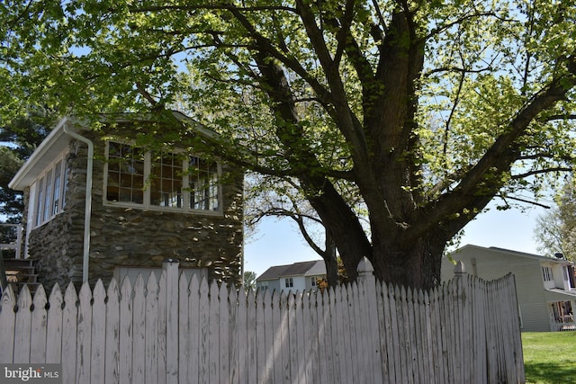 view of property exterior with fence and stone siding