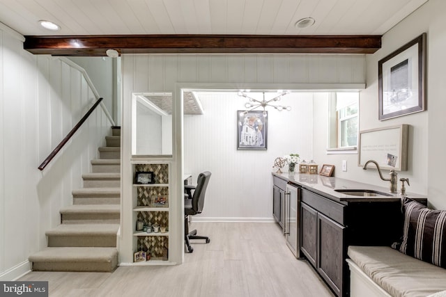 interior space with light wood finished floors, a sink, baseboards, an inviting chandelier, and beamed ceiling