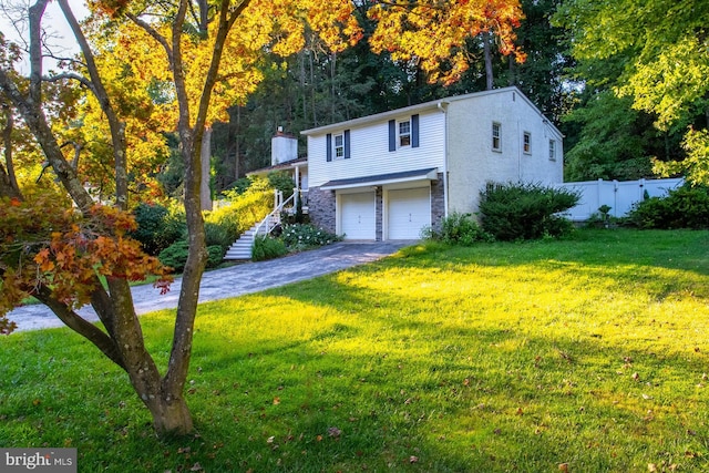 view of front of house with an attached garage, stairs, fence, and a front yard