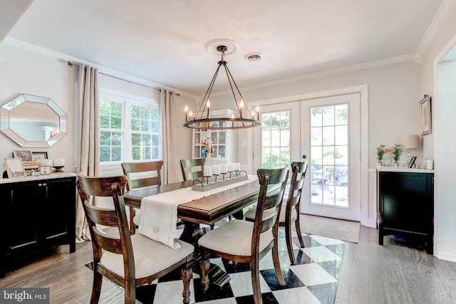 dining room with an inviting chandelier, ornamental molding, light wood-style floors, and visible vents
