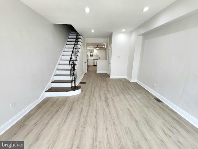 basement featuring baseboards, wood finished floors, stairs, and visible vents