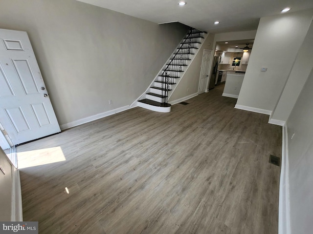 unfurnished living room featuring a ceiling fan, wood finished floors, stairs, baseboards, and recessed lighting