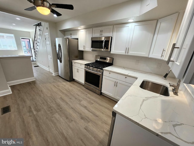 kitchen featuring white cabinets, stainless steel appliances, a sink, visible vents, and decorative backsplash