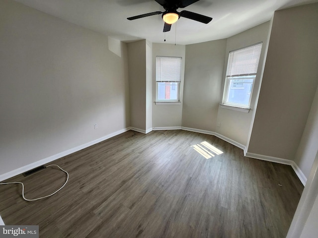 unfurnished room featuring baseboards, a ceiling fan, dark wood-type flooring, and visible vents