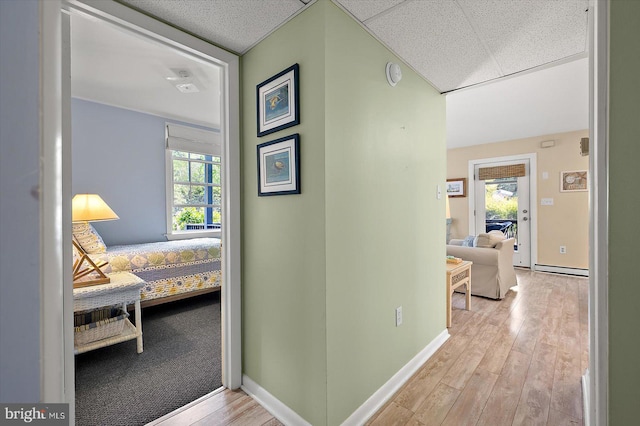 corridor with baseboards, a baseboard heating unit, and wood finished floors