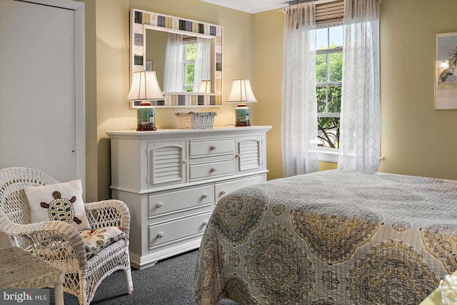 bedroom with ornamental molding and dark carpet