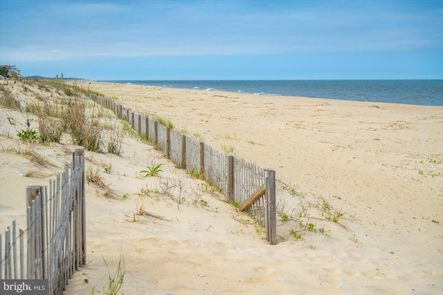 property view of water with fence and a view of the beach