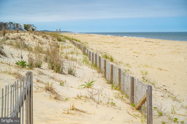 exterior space with a water view, fence, and a beach view