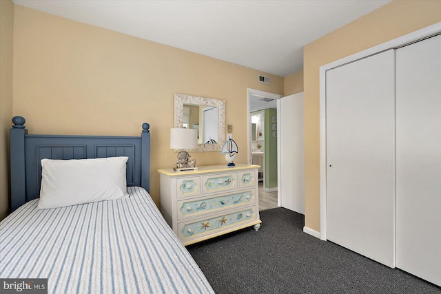 bedroom with baseboards, a closet, dark colored carpet, and visible vents