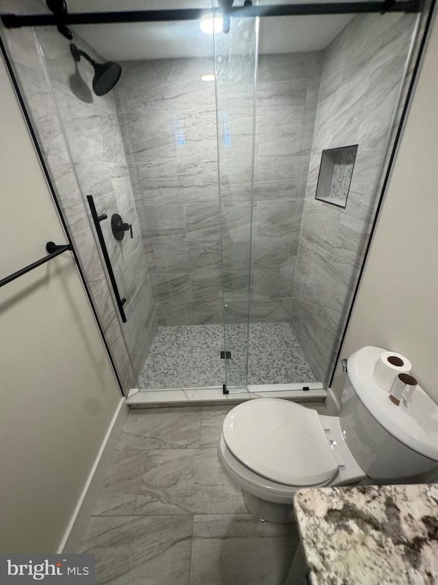 bathroom featuring a stall shower, toilet, baseboards, and marble finish floor