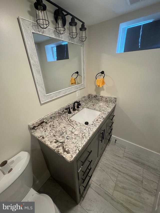 bathroom with toilet, baseboards, and vanity