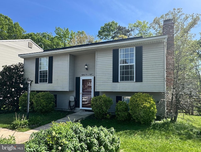 bi-level home with a chimney and a front yard