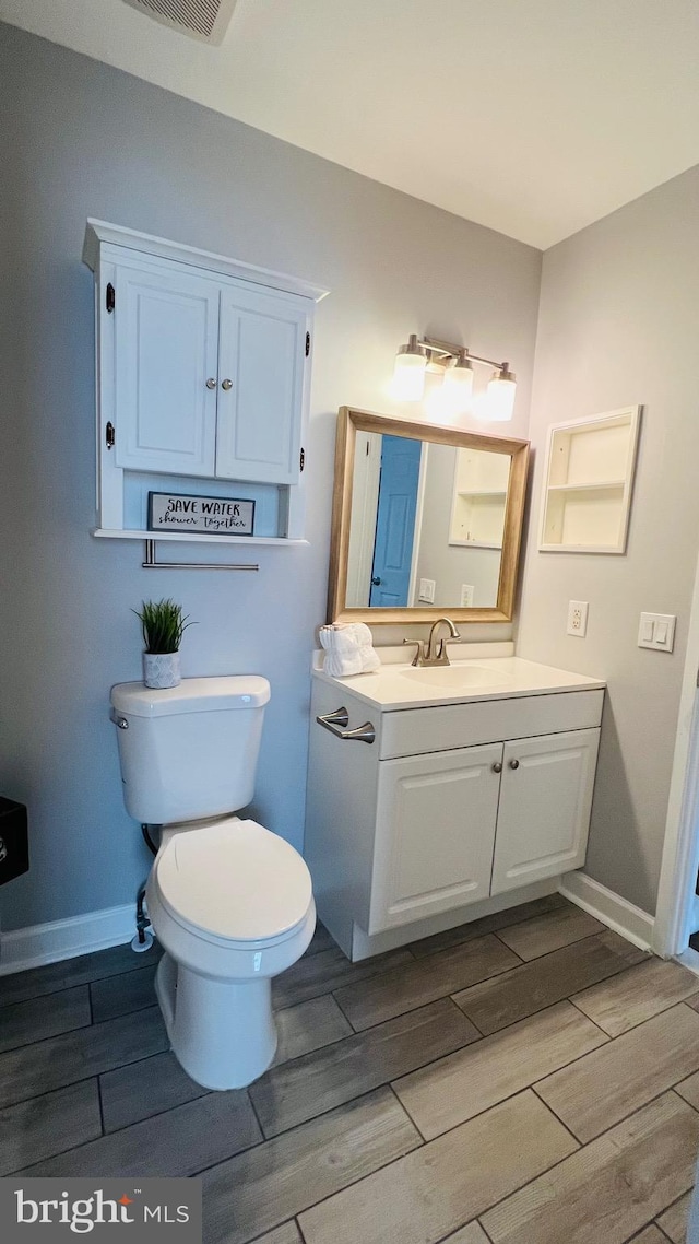 bathroom featuring wood tiled floors, toilet, baseboards, and vanity