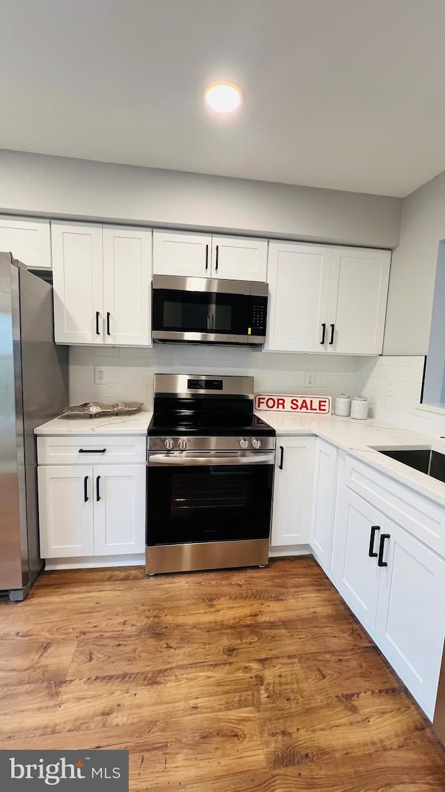kitchen featuring stainless steel appliances, white cabinetry, light countertops, light wood-type flooring, and recessed lighting