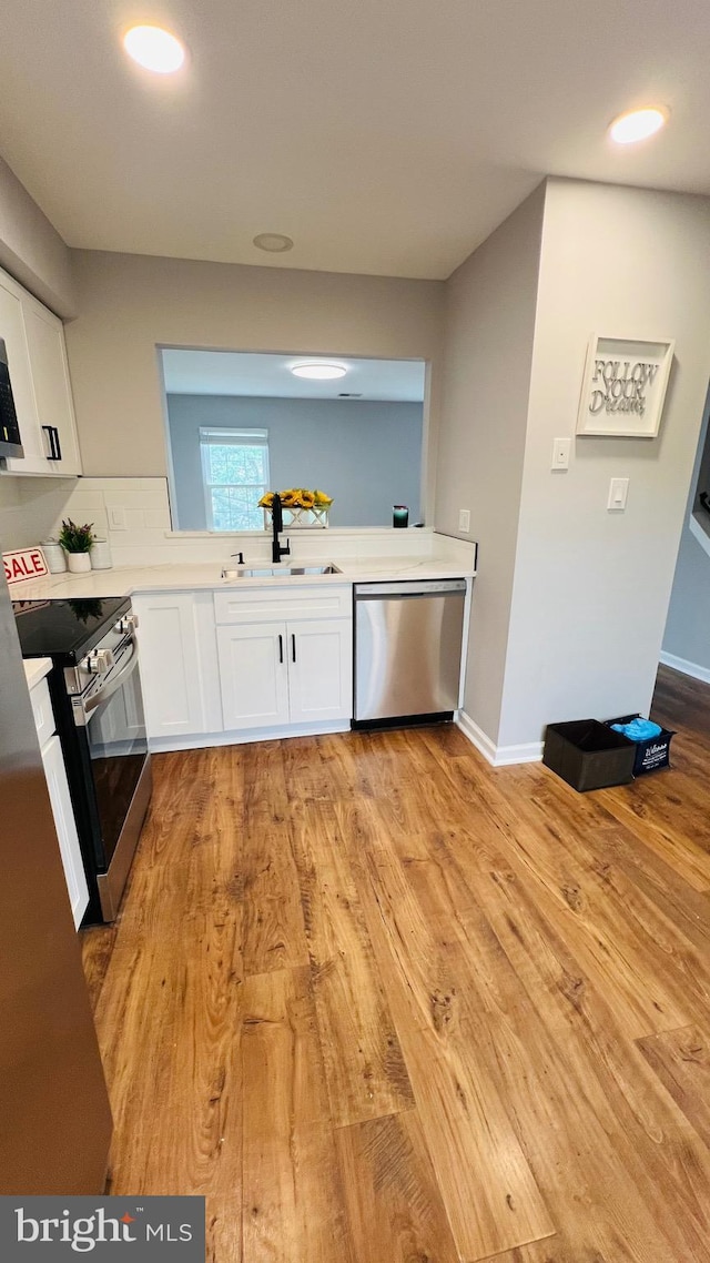 kitchen featuring stainless steel appliances, a sink, white cabinetry, light countertops, and recessed lighting