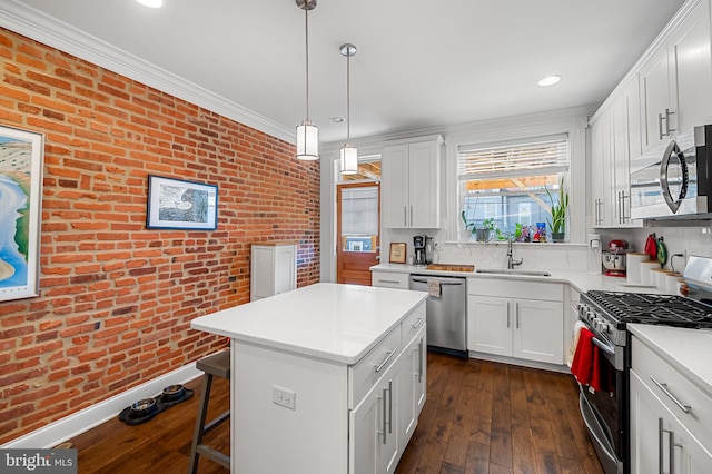 kitchen with a sink, brick wall, stainless steel appliances, light countertops, and dark wood-style floors