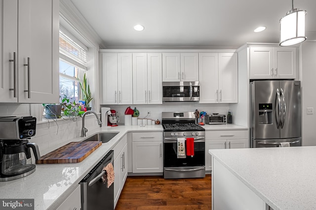 kitchen with tasteful backsplash, a sink, hanging light fixtures, white cabinets, and appliances with stainless steel finishes