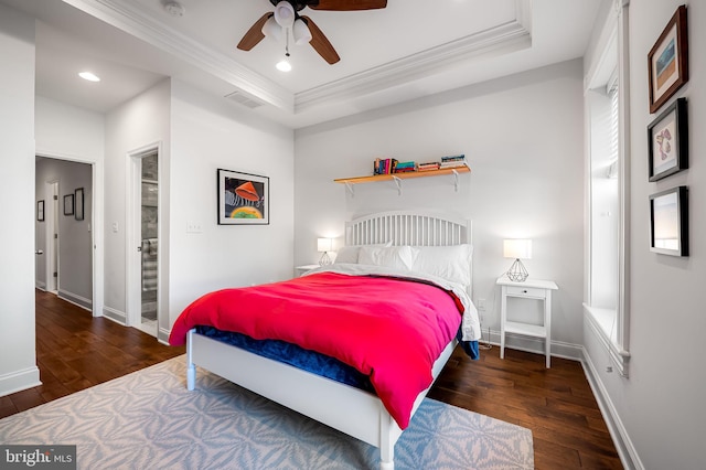 bedroom with a tray ceiling, visible vents, crown molding, baseboards, and hardwood / wood-style flooring