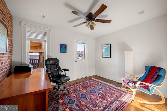 office area featuring baseboards, recessed lighting, brick wall, a ceiling fan, and wood finished floors